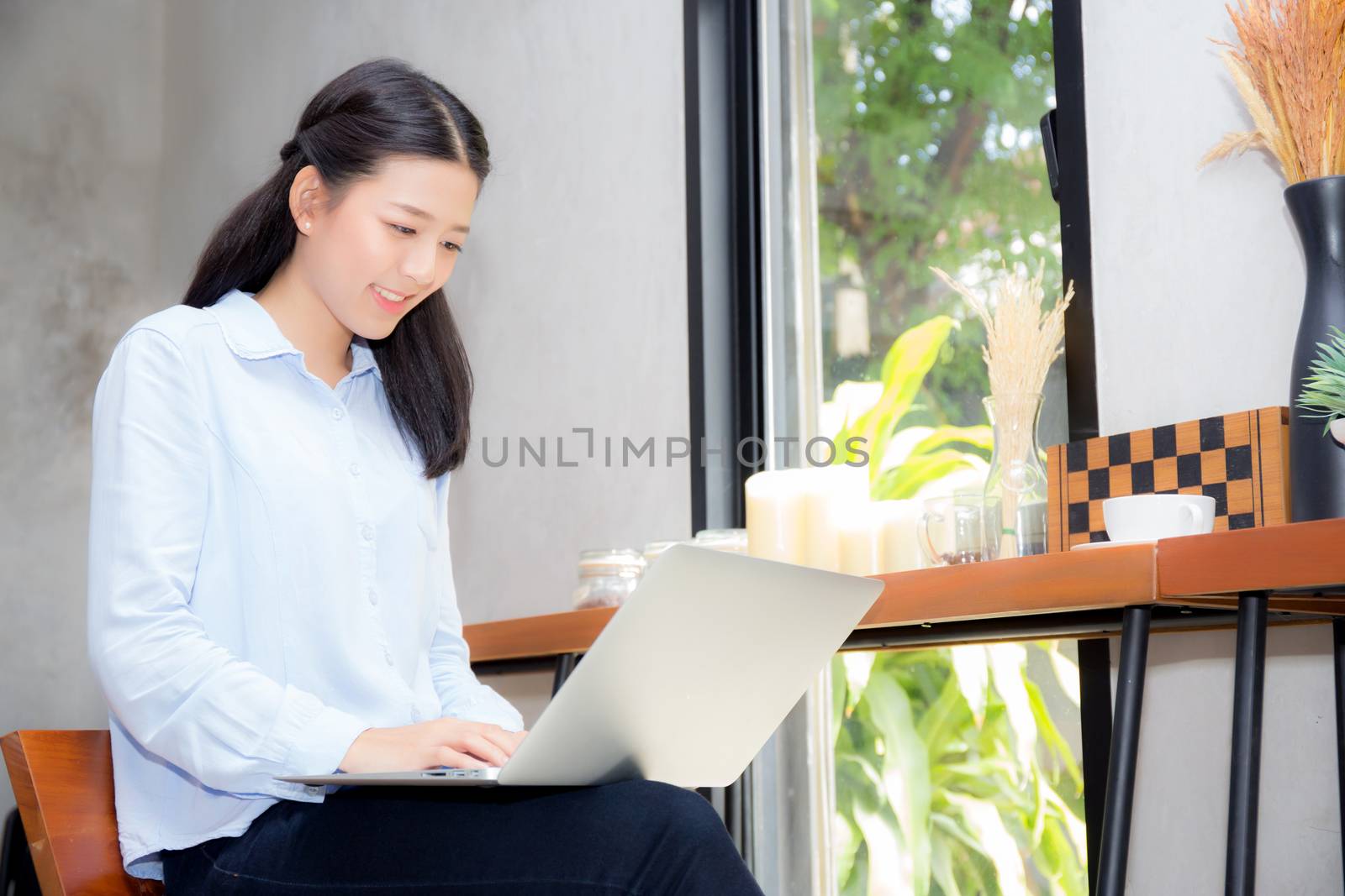 Beautiful asian young woman working online on laptop sitting at coffee shop, professional female freelancer using notebook computer with connect to internet for distance job.