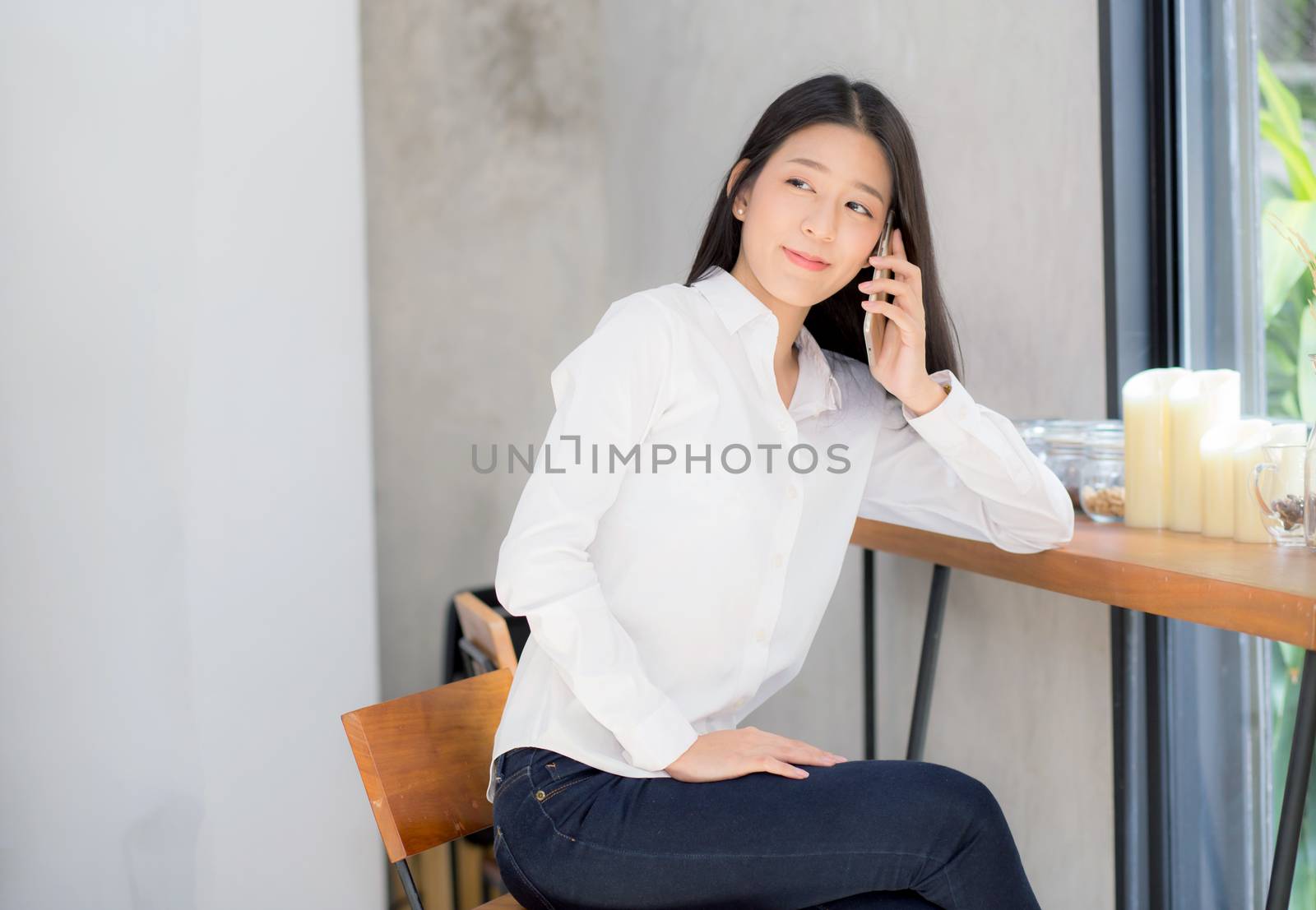 Beautiful young asian woman talking phone and smile in the coffee shop, businesswoman sitting in cafe free time, freelancer female calling telephone, communication concept.