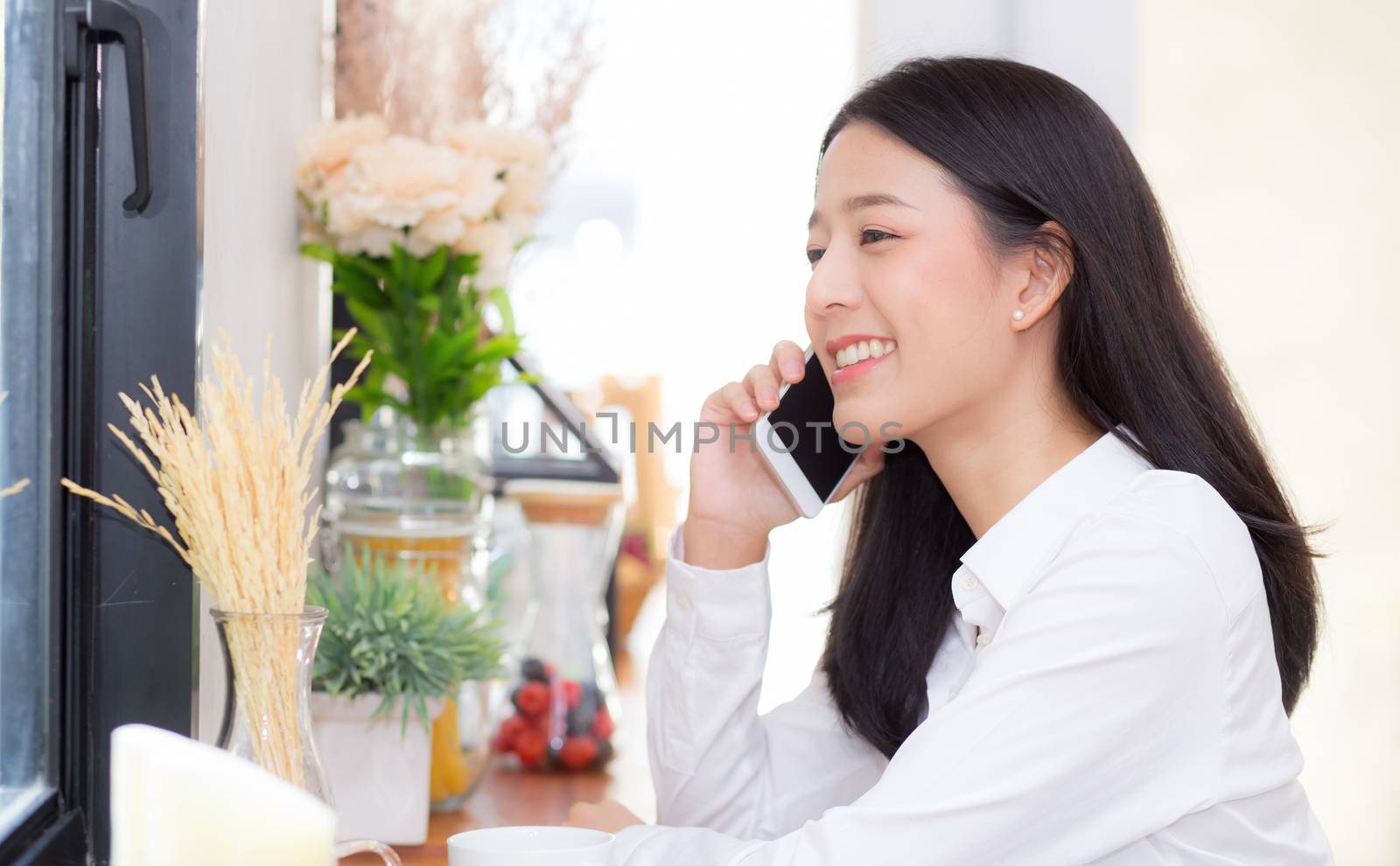 Beautiful young asian woman talking phone and smile in the coffe by nnudoo