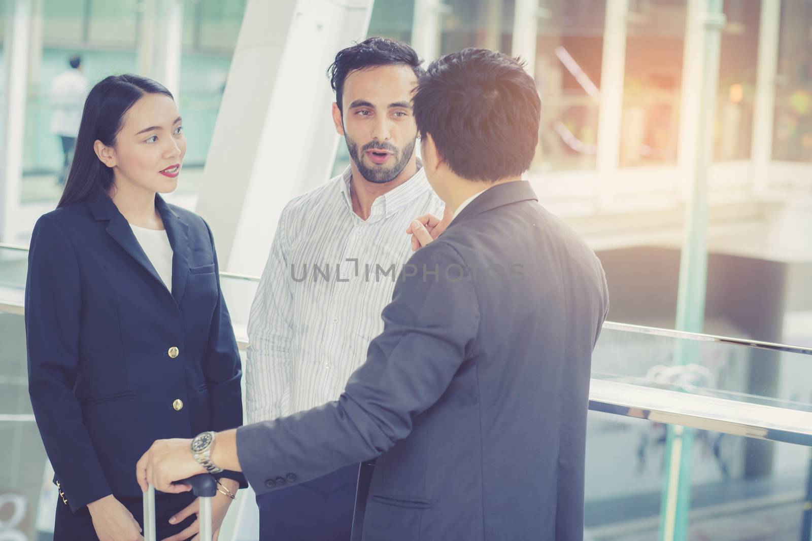 handsome asian young businessman and businesswoman three people in classic suits talking and smile with discussion standing outside the office building, teamwork with business concept.