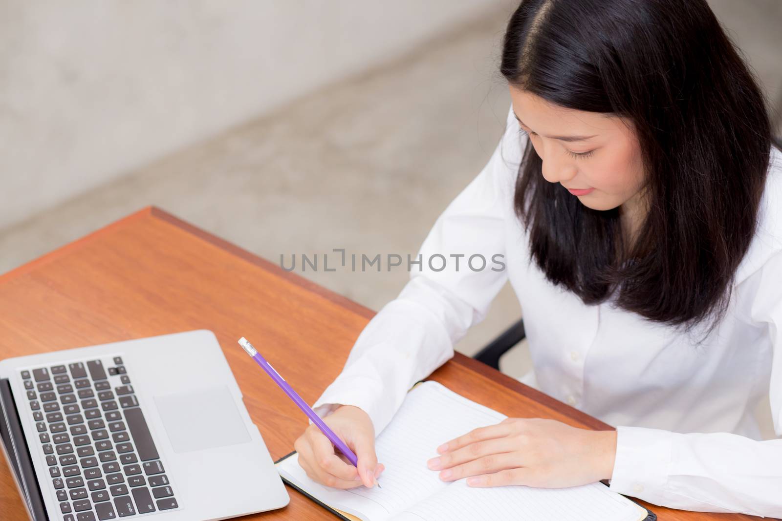 Business asian woman writing on notebook on table with laptop, girl work at coffee shop, freelance business concept.