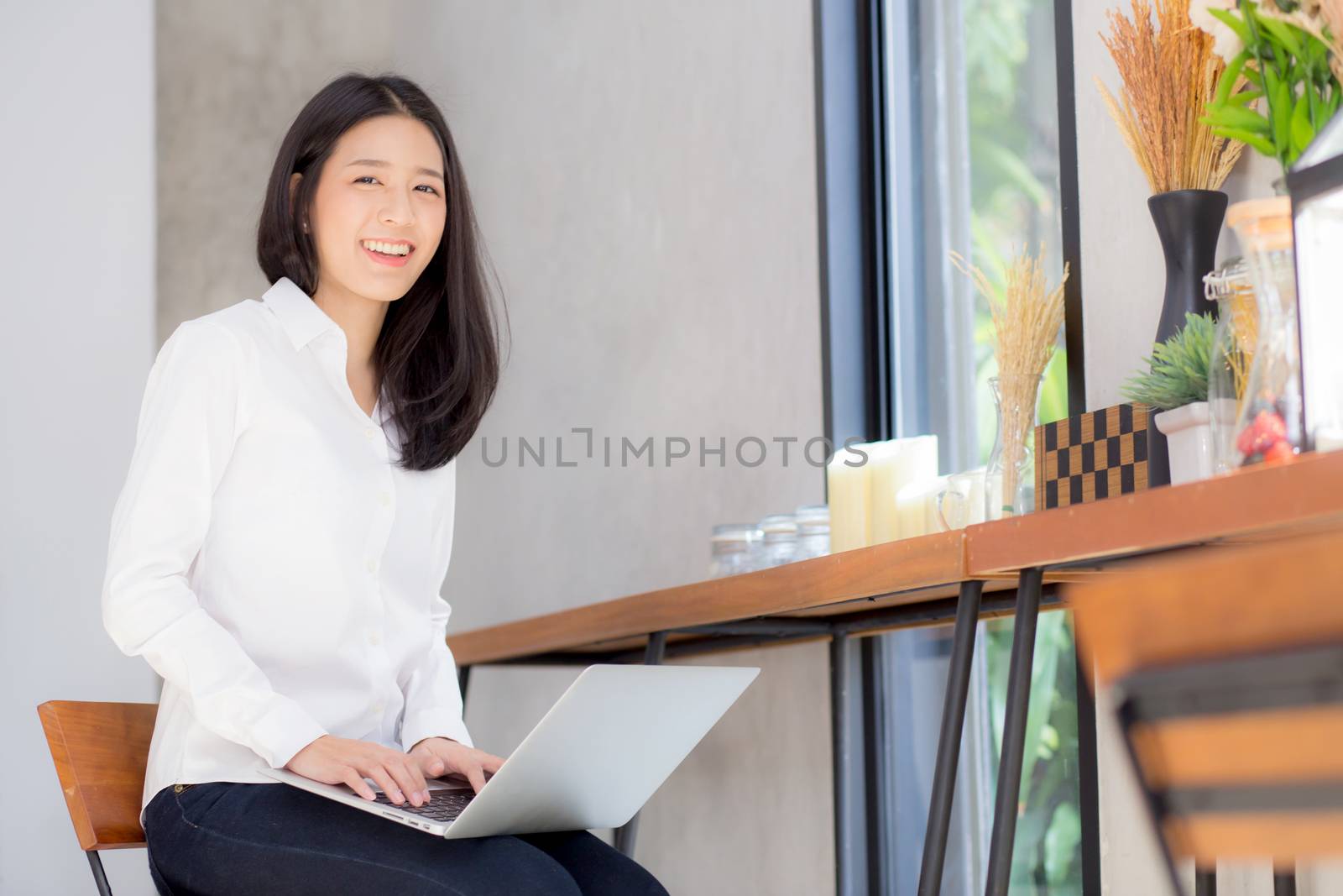 Beautiful asian young woman working online on laptop sitting at coffee shop, professional female freelancer using notebook computer with connect to internet for distance job.