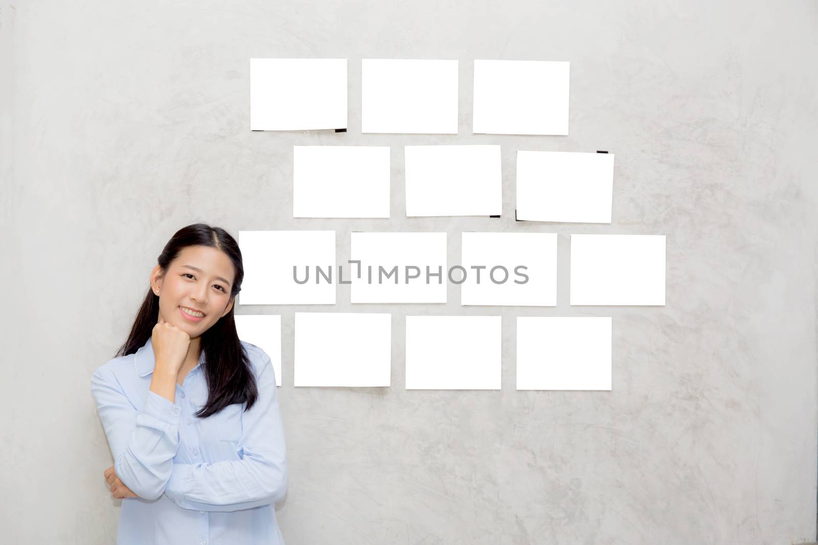 Beautiful asian young woman standing with picture gallery copy space on wall texture cement background.