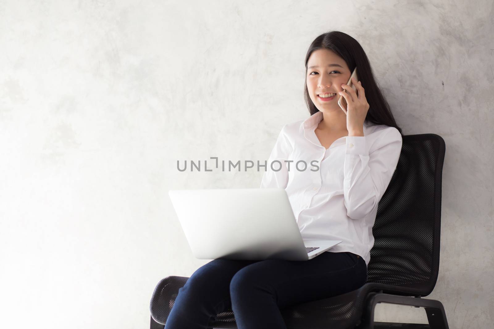Beautiful asian young businesswoman excited and glad of success with laptop, girl taking mobile phone and working coffee shop on cement background, career freelance business concept.