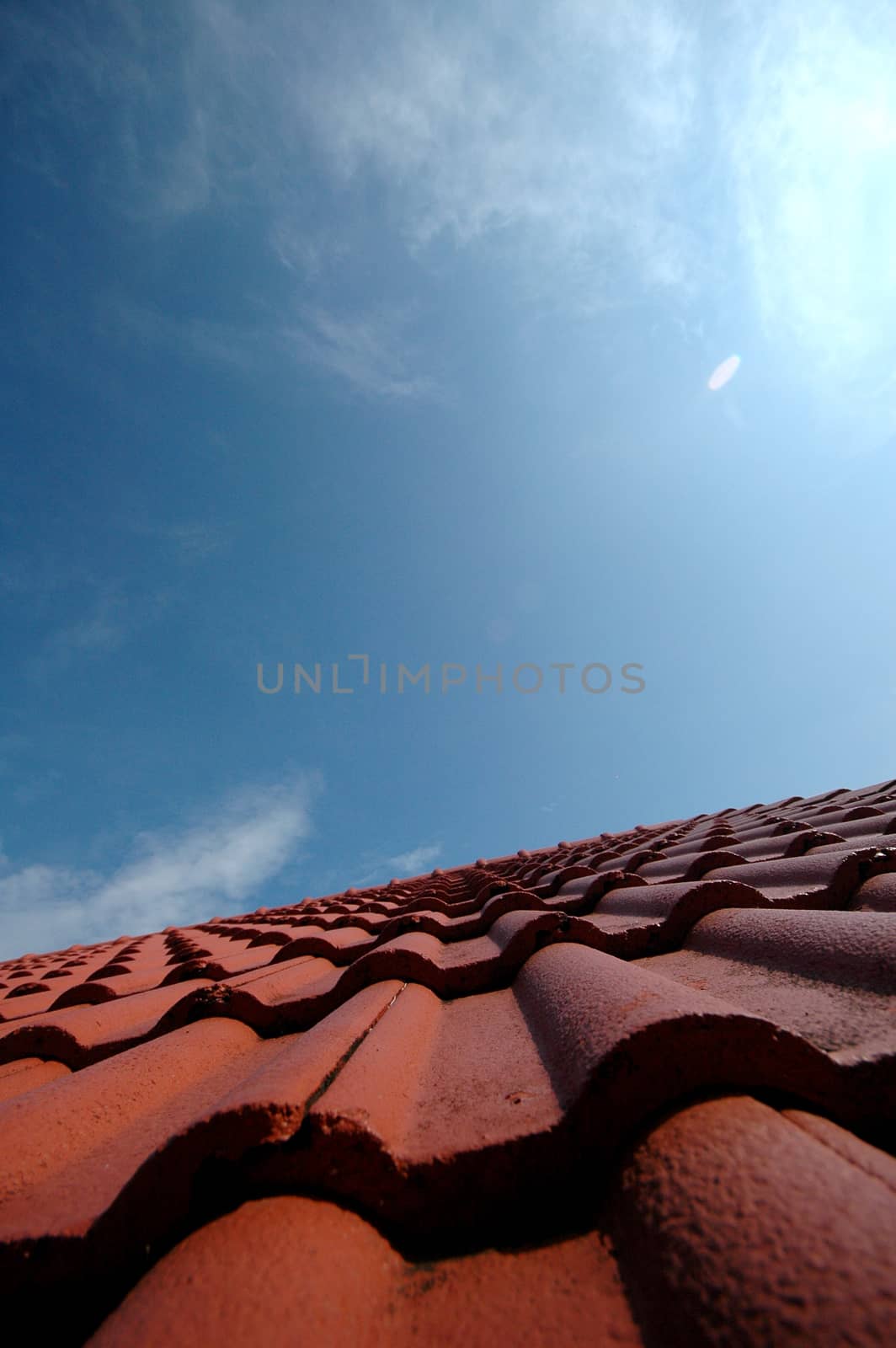 Red tiles on a house roof under blue sky by eyeofpaul