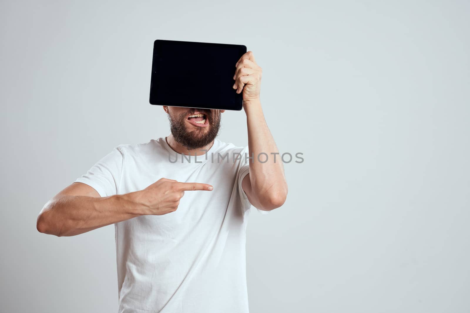 emotional man with a tablet in front of his eyes gesturing with his hands cropped view Copy Space Model light background. High quality photo