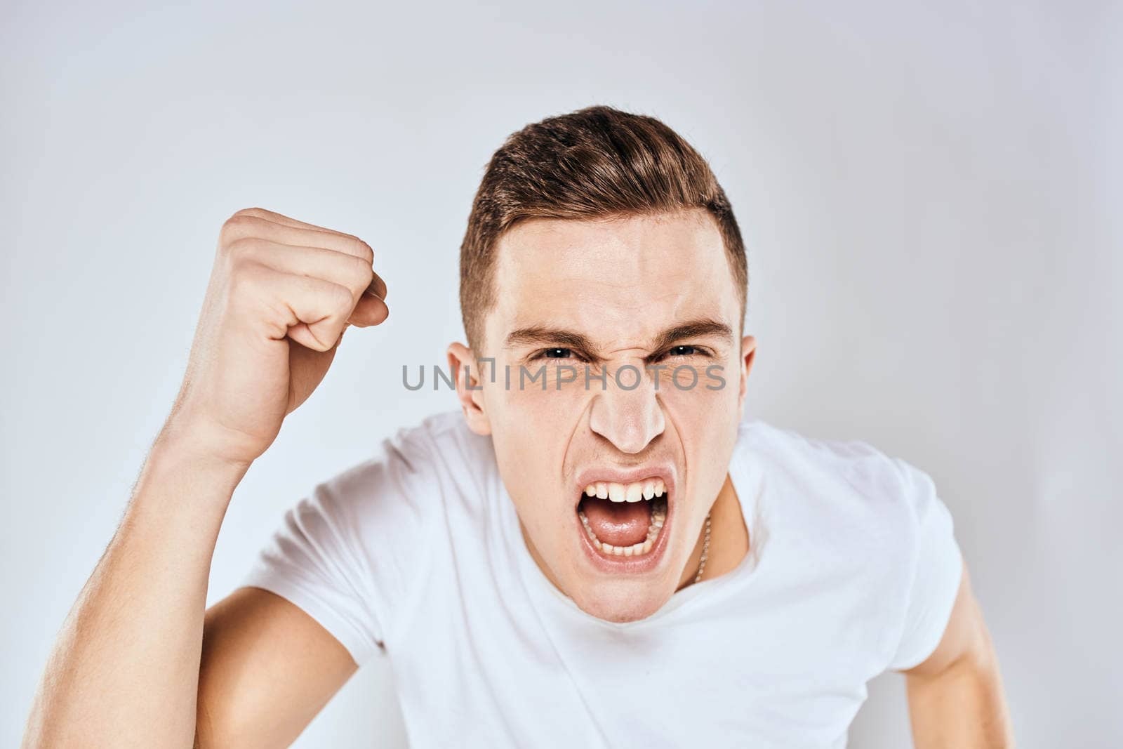 Man in white t-shirt displeased facial expression gesturing with hands studio lifestyle by SHOTPRIME