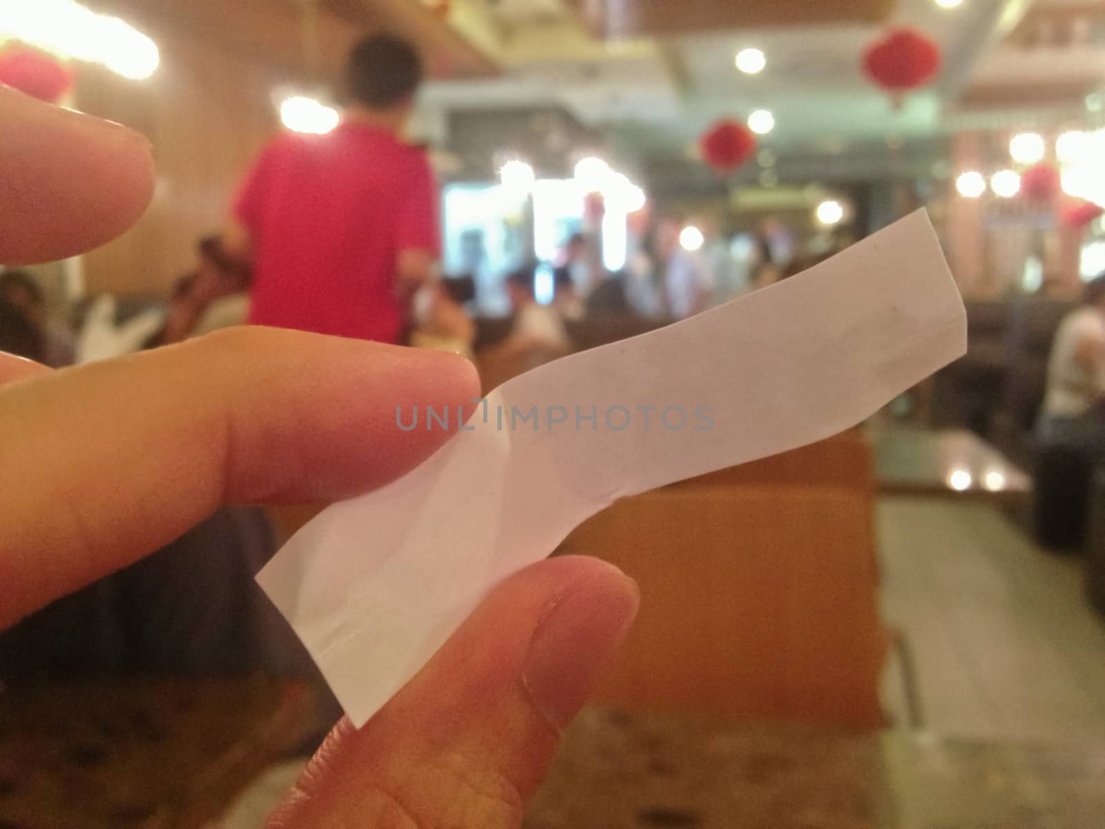 blank copy space paper tag holding by fingers. A person sits in Chinese restaurant.