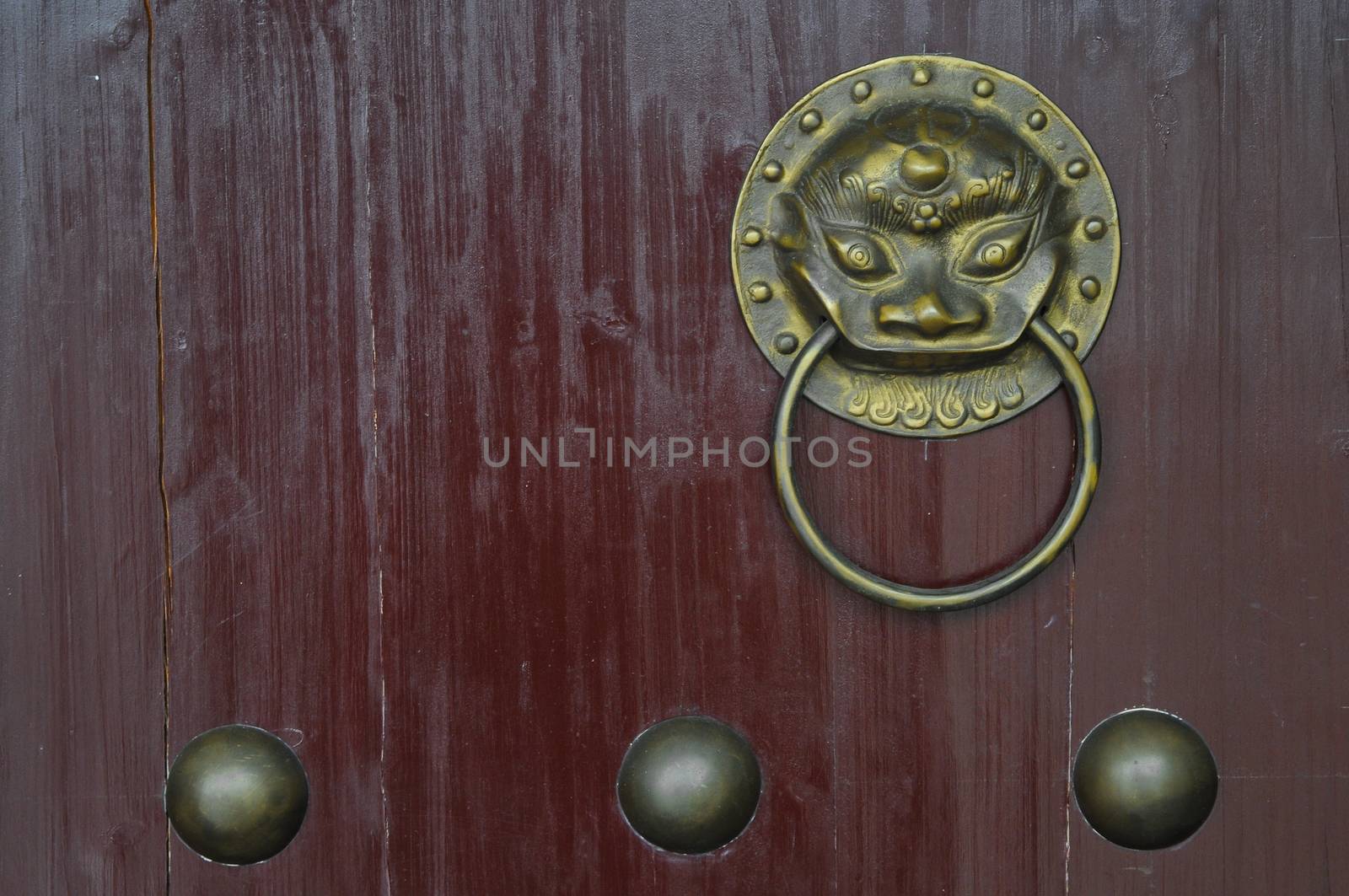 Vintage golden lion Chinese ornament door knob on red gate by eyeofpaul