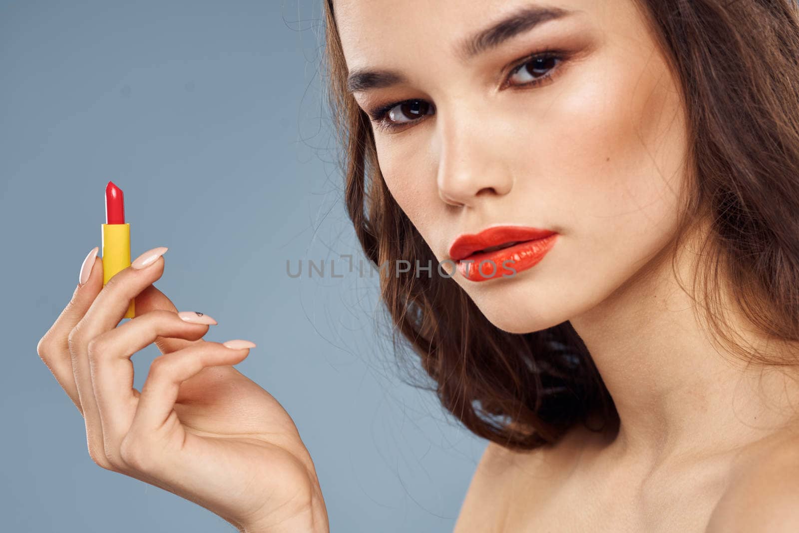 Woman with lipstick on a gray background brunette makeup with eye shadow on the eyelids. High quality photo