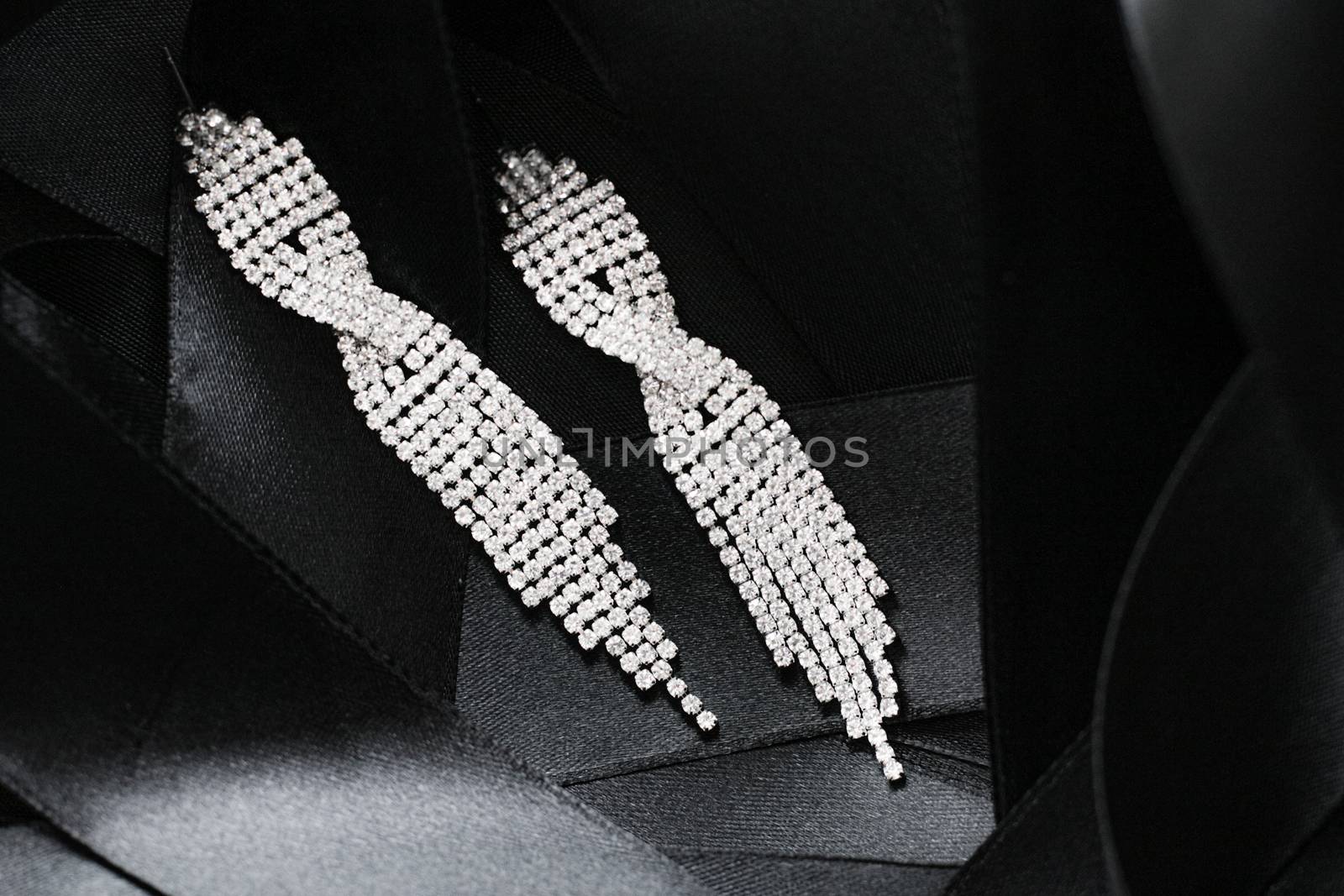 Luxury diamond earrings on black silk ribbon as background, jewe by Anneleven