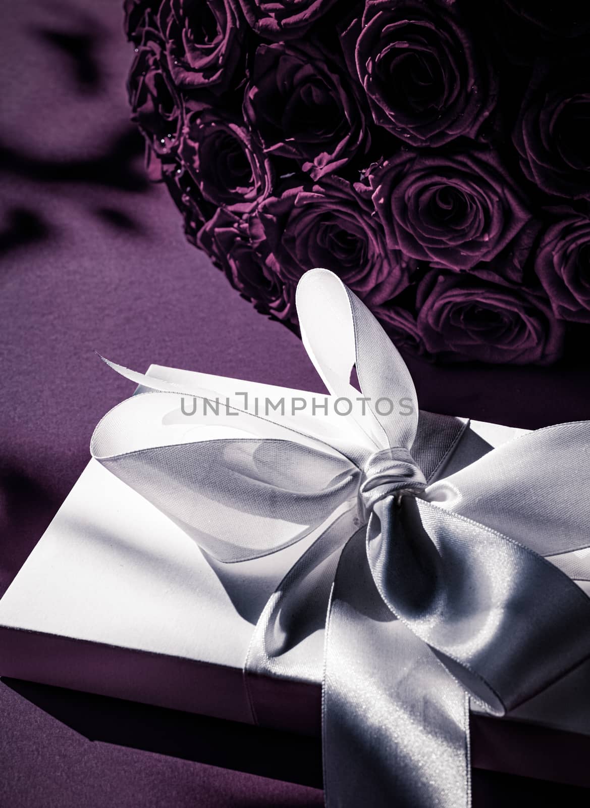 Luxury holiday silk gift box and bouquet of roses on purple back by Anneleven