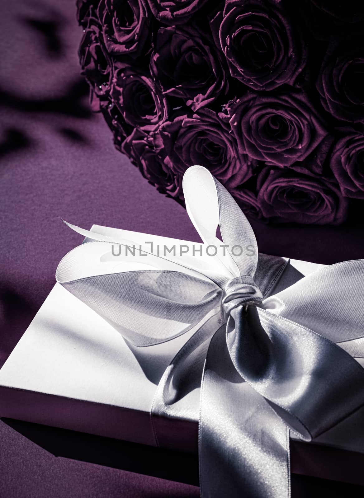 Happy holidays, luxe shopping and love gifts concept - Luxury holiday silk gift box and bouquet of roses on purple background, romantic surprise and flowers as birthday or Valentines Day present