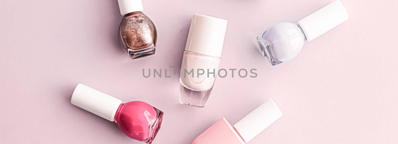 Nail polish bottles on blush pink background, beauty branding