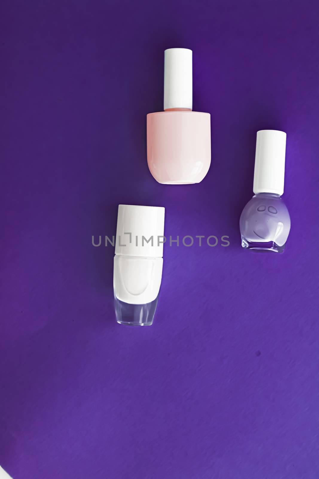 Nail polish bottles on dark purple background, beauty branding