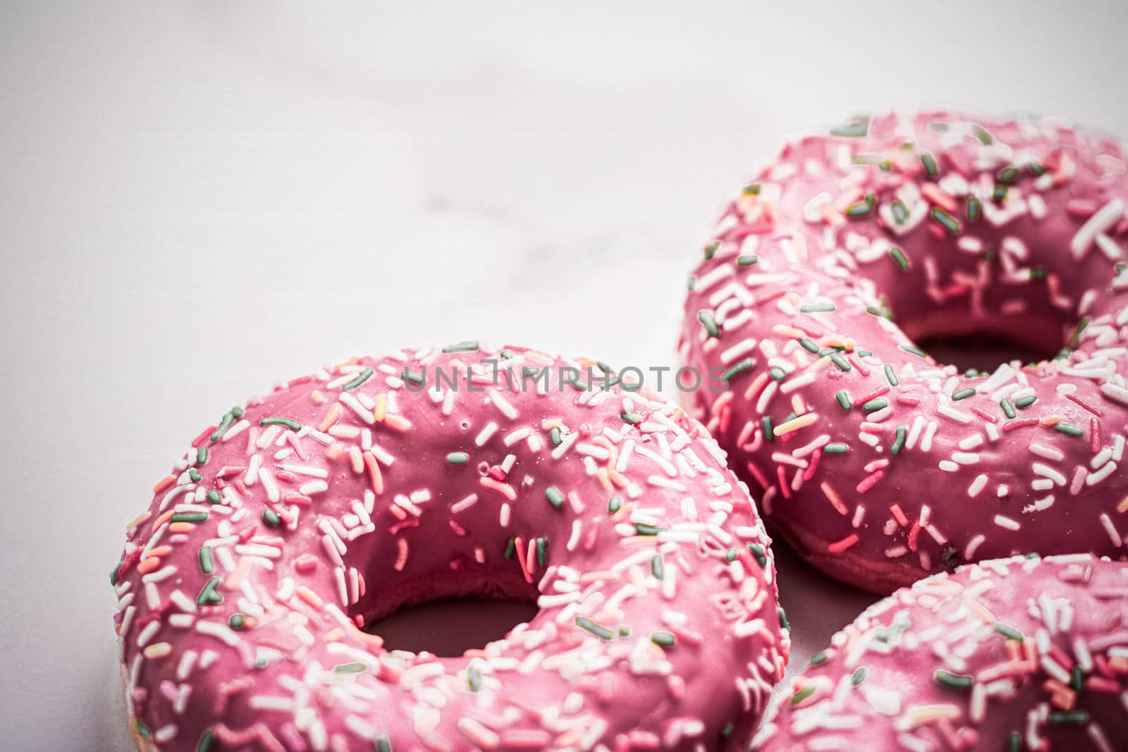 Frosted sprinkled donuts, sweet pastry dessert on marble table b by Anneleven