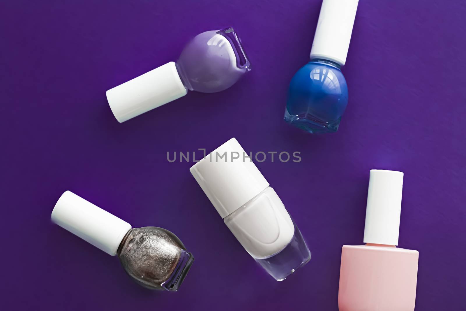 Nail polish bottles on dark purple background, beauty branding