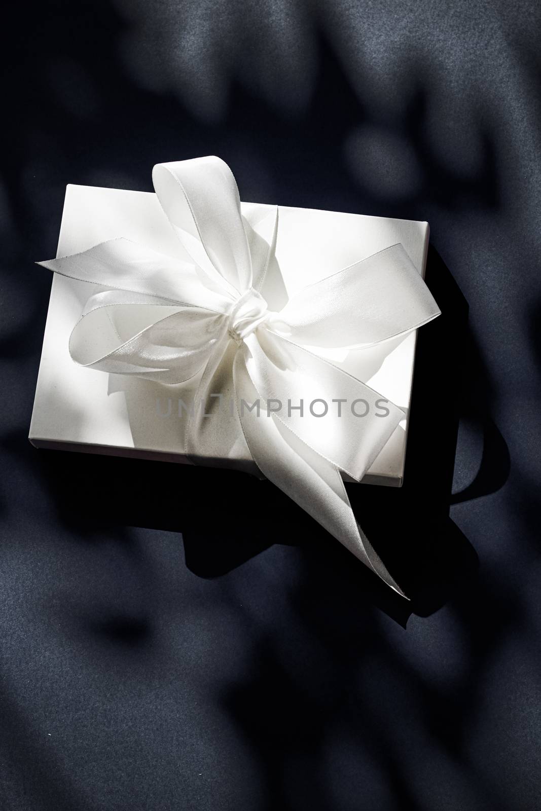 Anniversary celebration, shop sale promotion and luxe surprise concept - Luxury holiday white gift box with silk ribbon and bow on black background, luxe wedding or birthday present