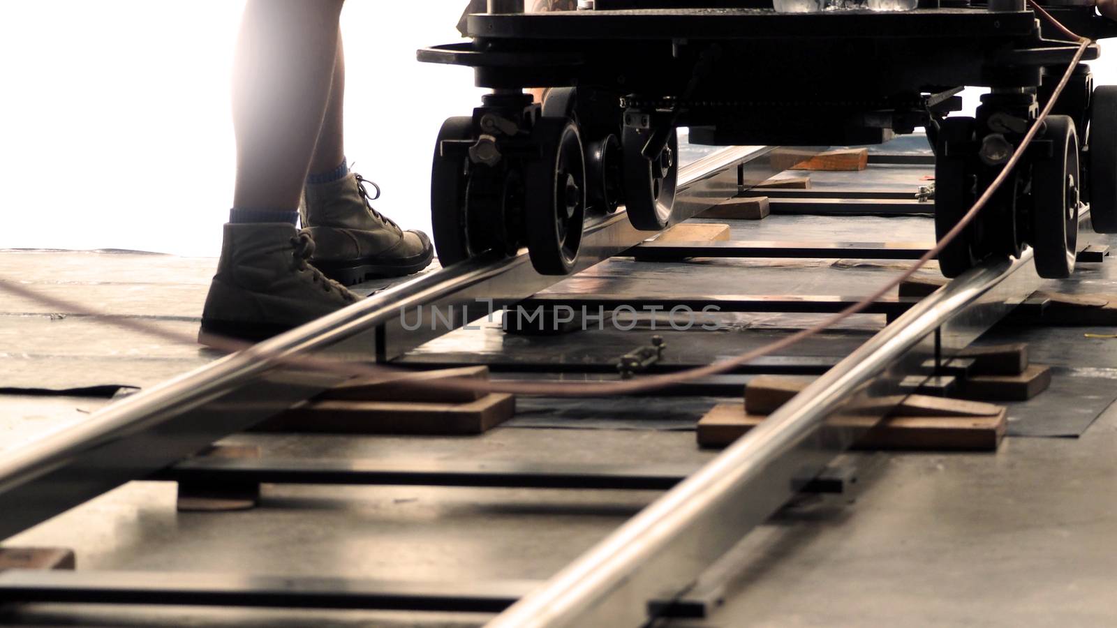 Behind the scenes of production team setting dolly track for video camera equipment before movie shooting in a big studio. 