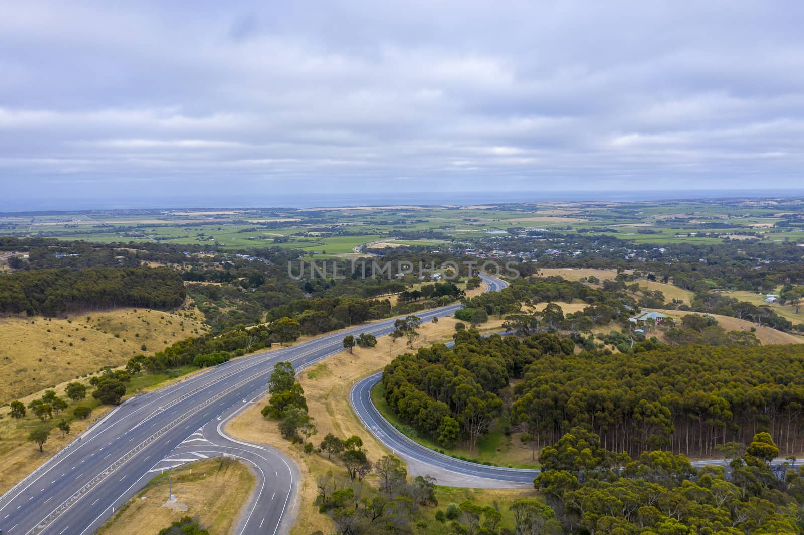 Aerial view of an arterial road running through green fields in regional Australia