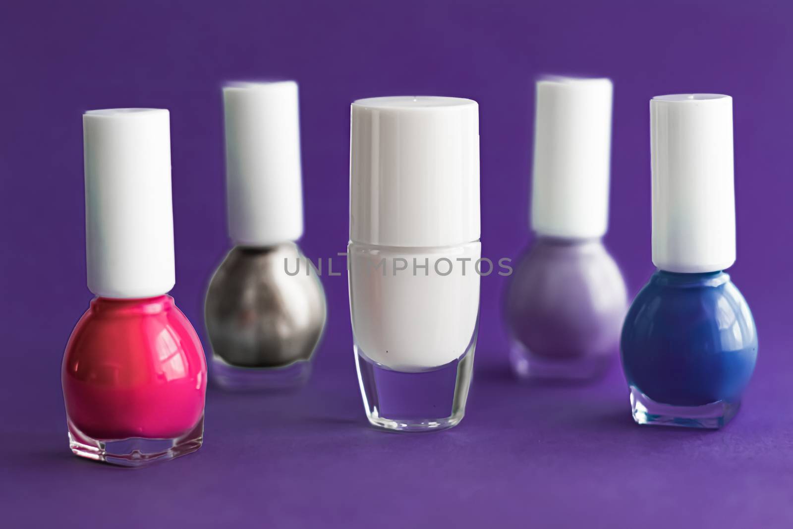 Nail polish bottles on dark purple background, beauty branding