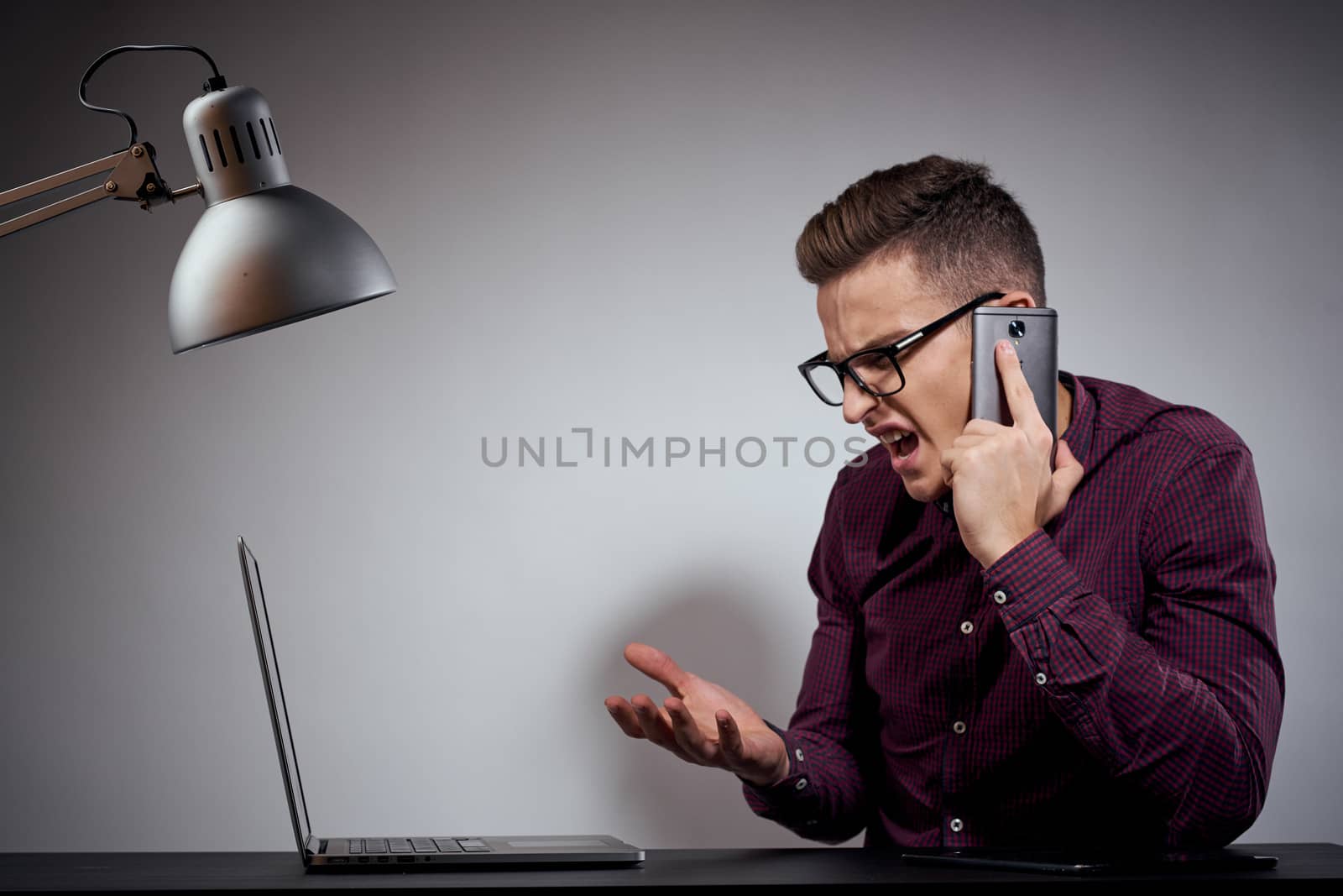 businessman in glasses and a shirt sits at a table with open laptops Coffee Space mobile phone. High quality photo