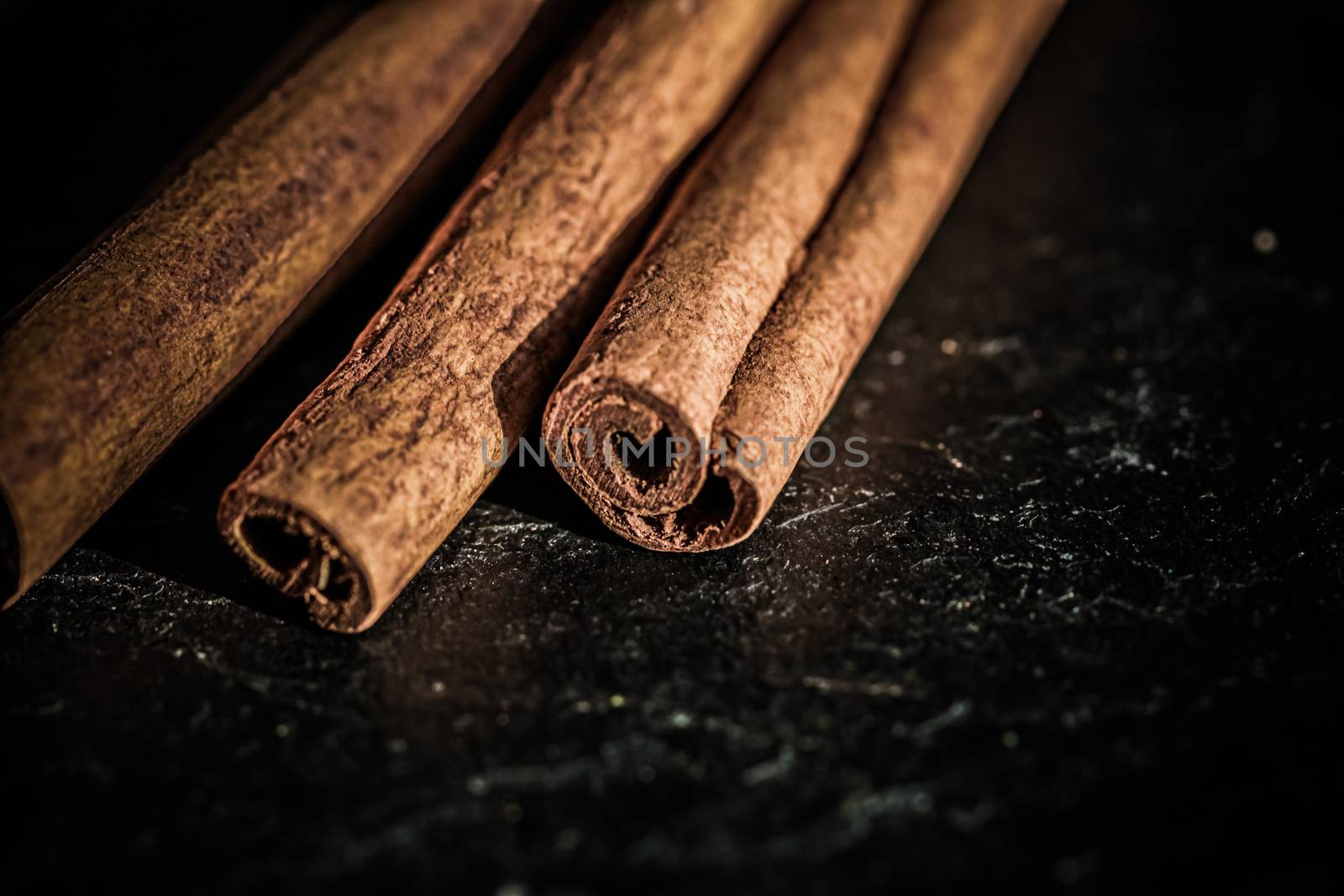 Cinnamon sticks on black stone background, food recipes