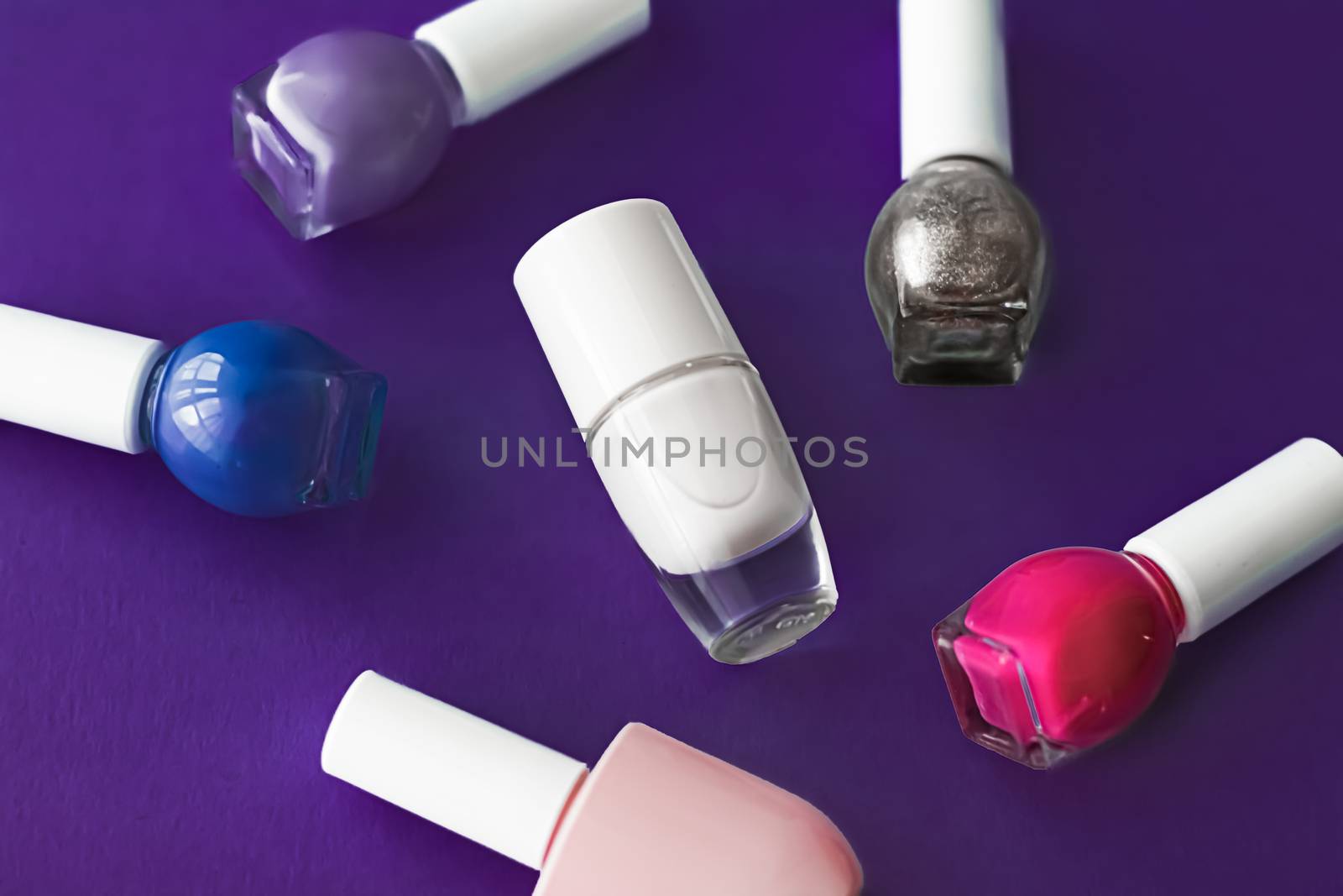 Nail polish bottles on dark purple background, beauty branding