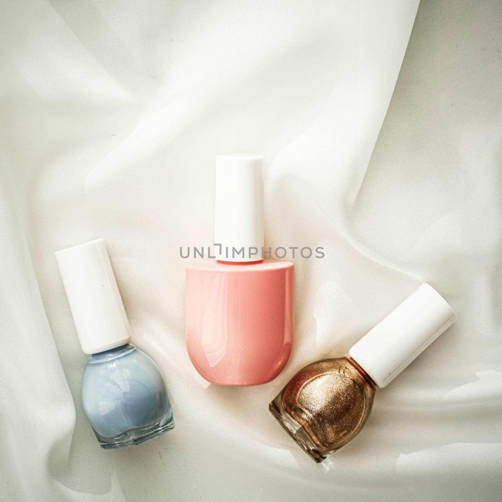 Nail polish bottles on silk background, french manicure products by Anneleven