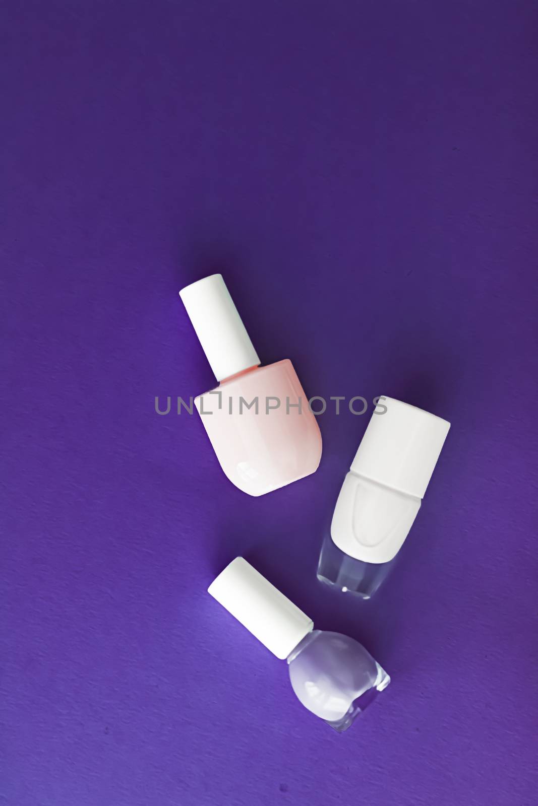 Nail polish bottles on dark purple background, beauty branding