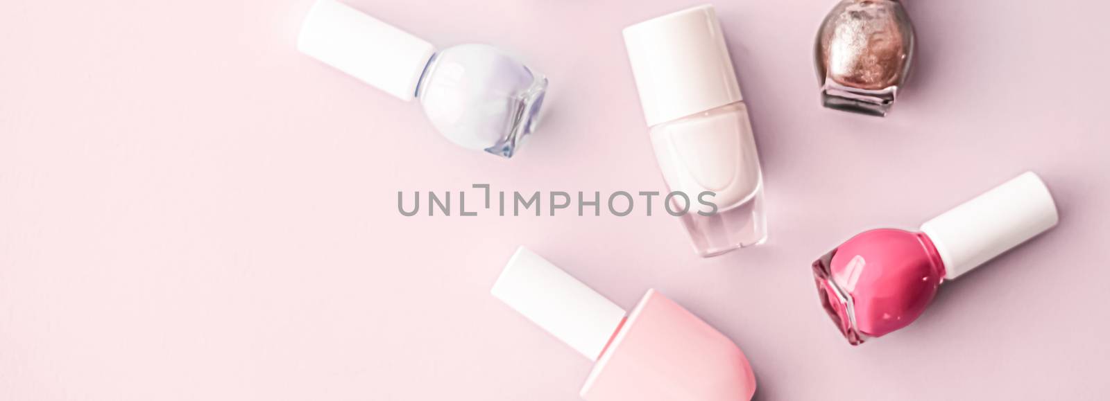 Nail polish bottles on blush pink background, beauty branding