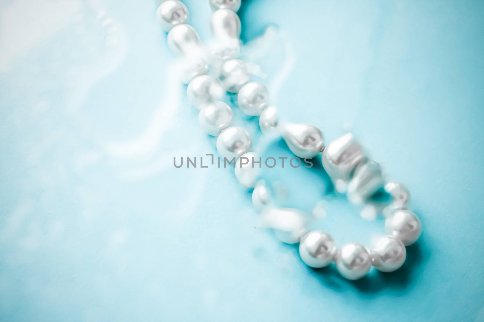 Coastal jewellery fashion, pearl necklace under blue water backg by Anneleven