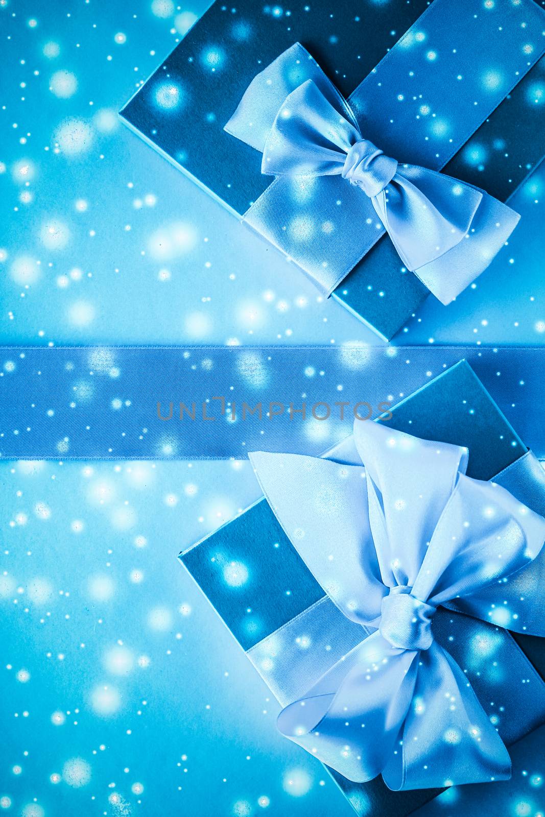 New Years Eve celebration, wrapped luxury boxes and cold season concept - Winter holiday gifts and glowing snow on frozen blue background, Christmas presents surprise