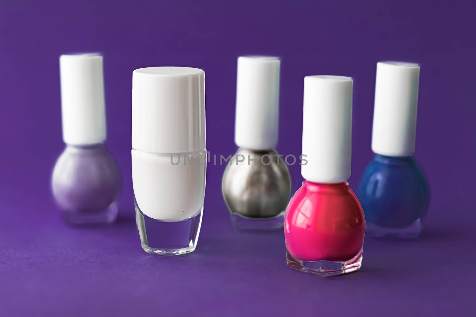 Nail polish bottles on dark purple background, beauty branding