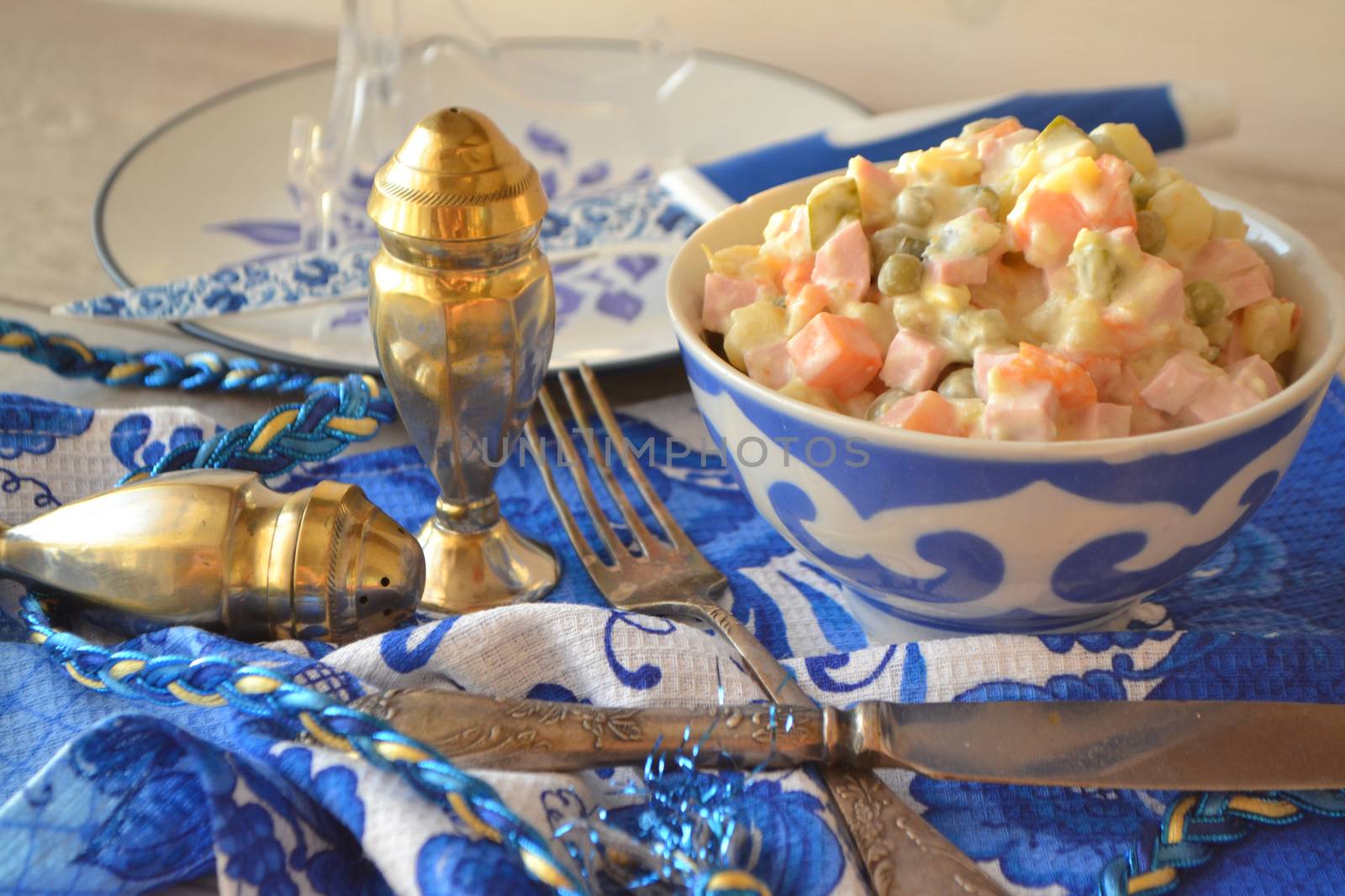 Russian cuisine: salad Olivier in blue and white bowl in gzhel style.