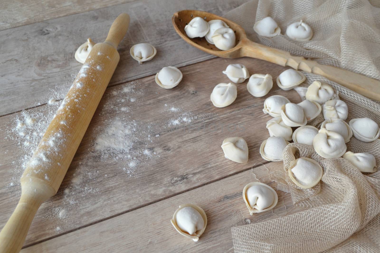 Raw dumplings with rolled for homemade russian pelmeni. On white rustic background