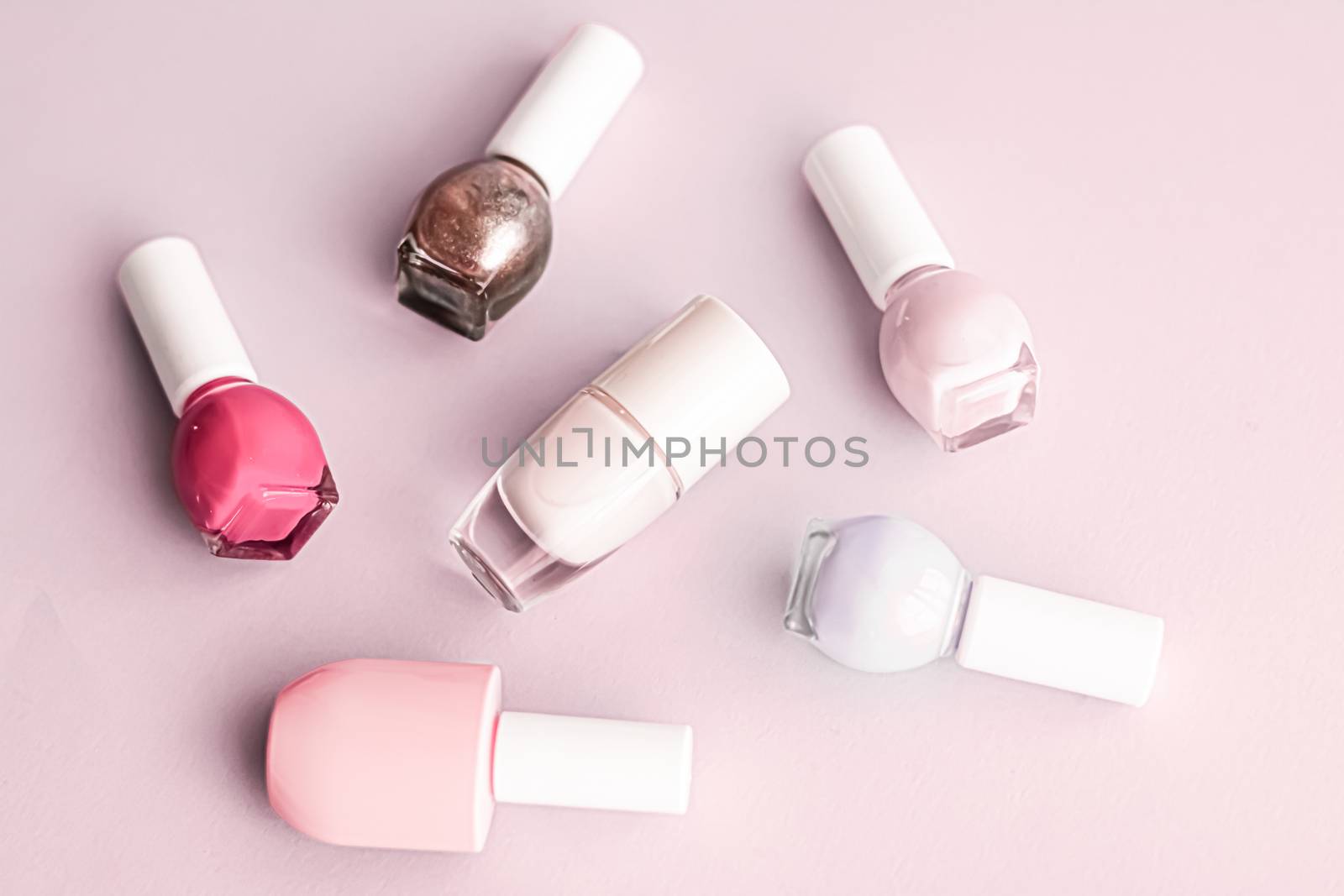 Nail polish bottles on blush pink background, beauty brand by Anneleven