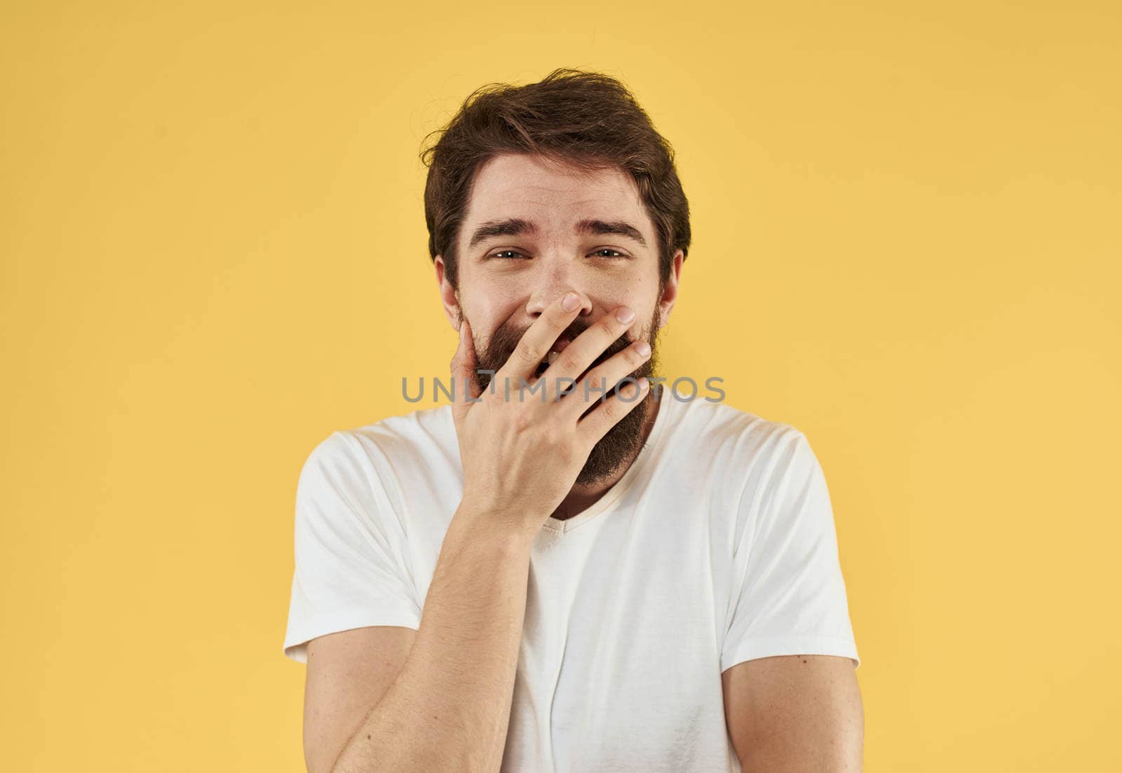 Portrait of a guy in a t-shirt and a brunet beard model yellow background. High quality photo