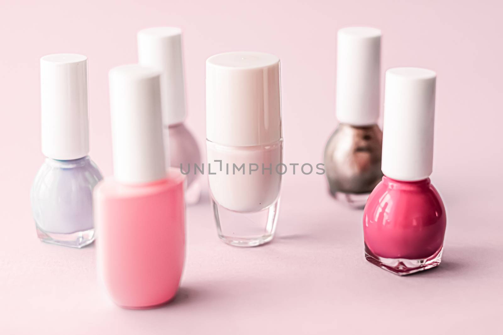 Nail polish bottles on blush pink background, beauty branding