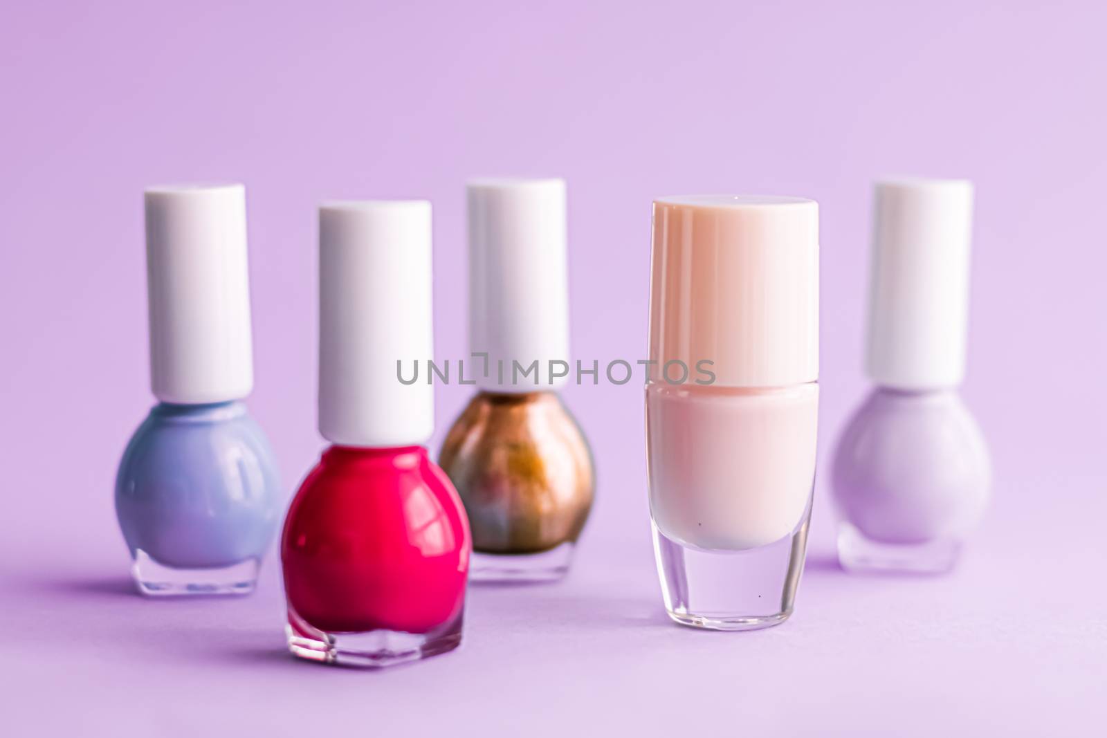 Nail polish bottles on purple background, beauty branding