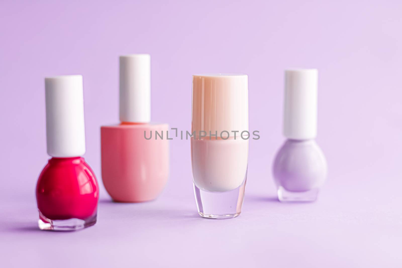 Nail polish bottles on purple background, beauty branding