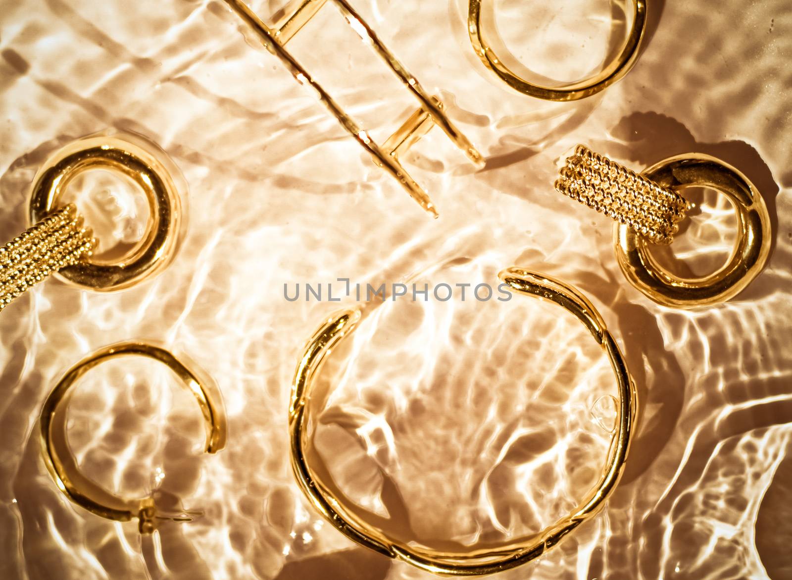 Jewellery branding, fashion gift and luxe shopping concept - Golden bracelets, earrings, rings, jewelery on gold water background, luxury glamour and holiday beauty design for jewelry brand ads