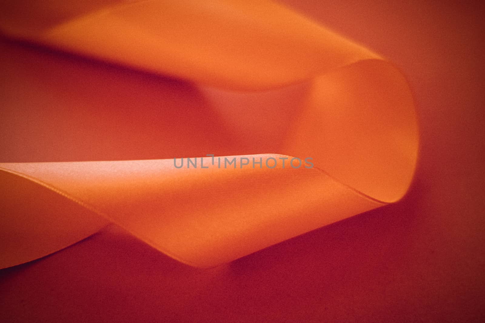 Branding, holidays and luxe brands concept - Abstract curly silk ribbon on orange background, exclusive luxury brand design for holiday sale product promotion and glamour art invitation card backdrop