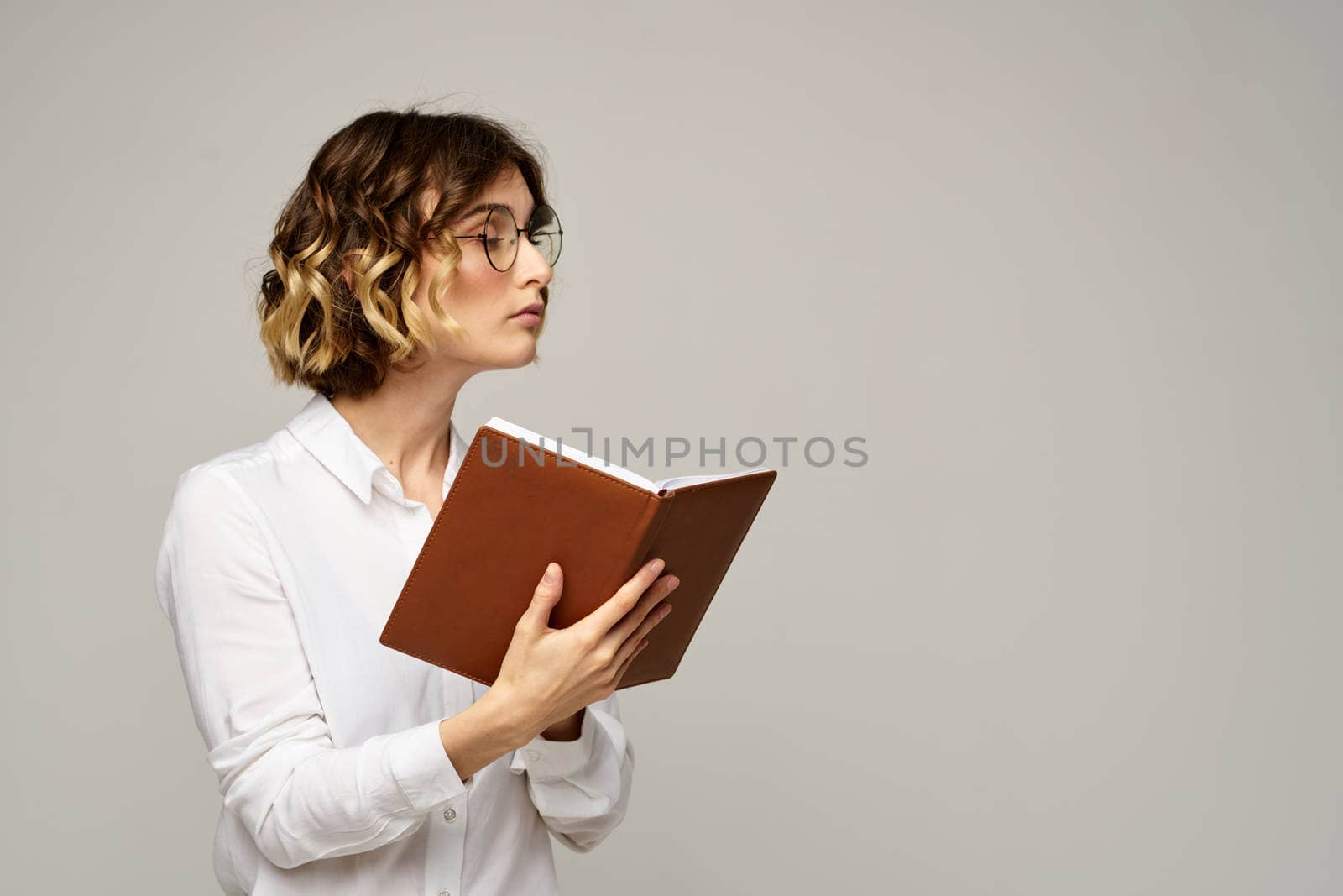 woman with notepad in hands business work beige background glasses hairstyle. High quality photo