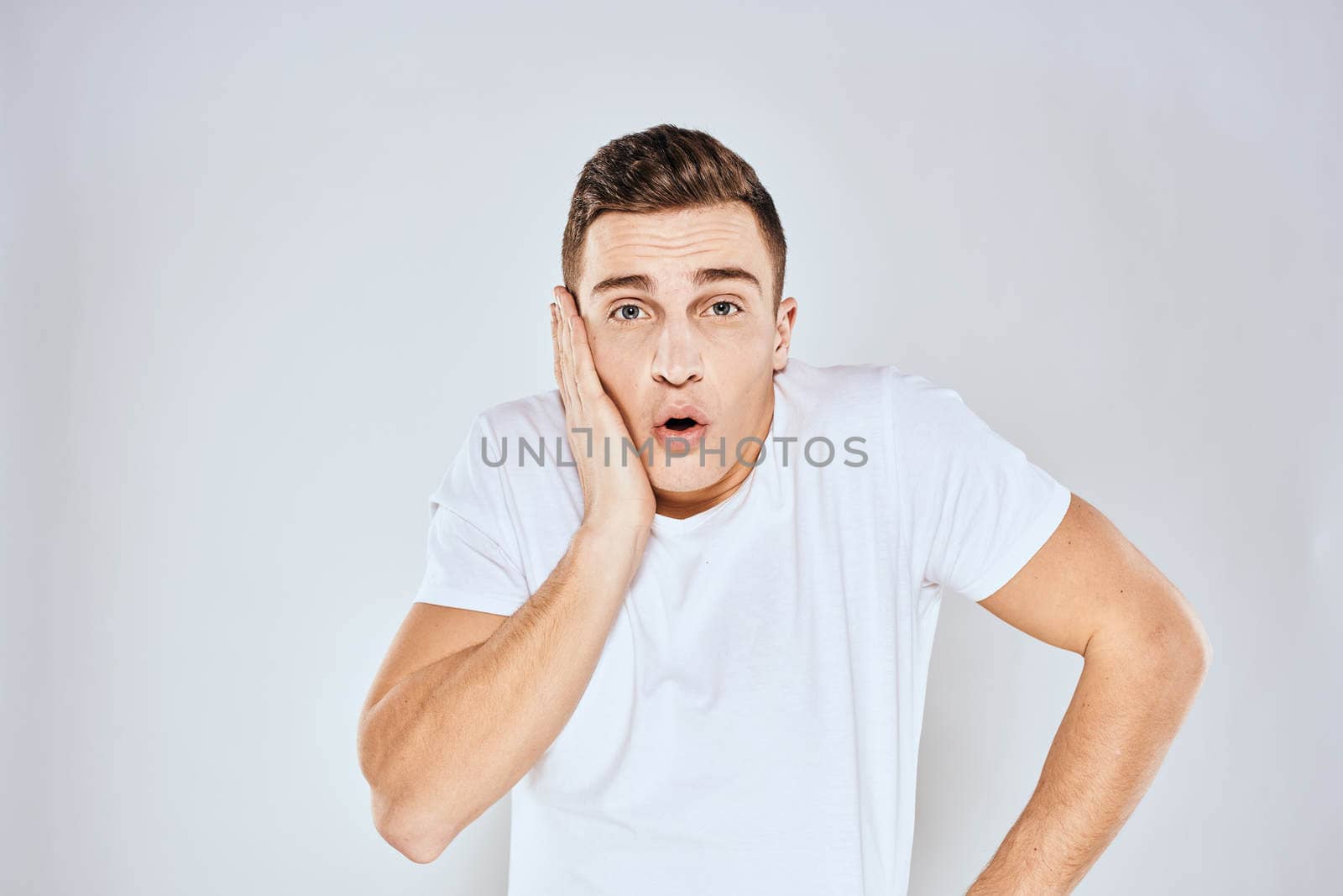 Nice man in a white t-shirt gestures with his hands emotions surprise studio by SHOTPRIME