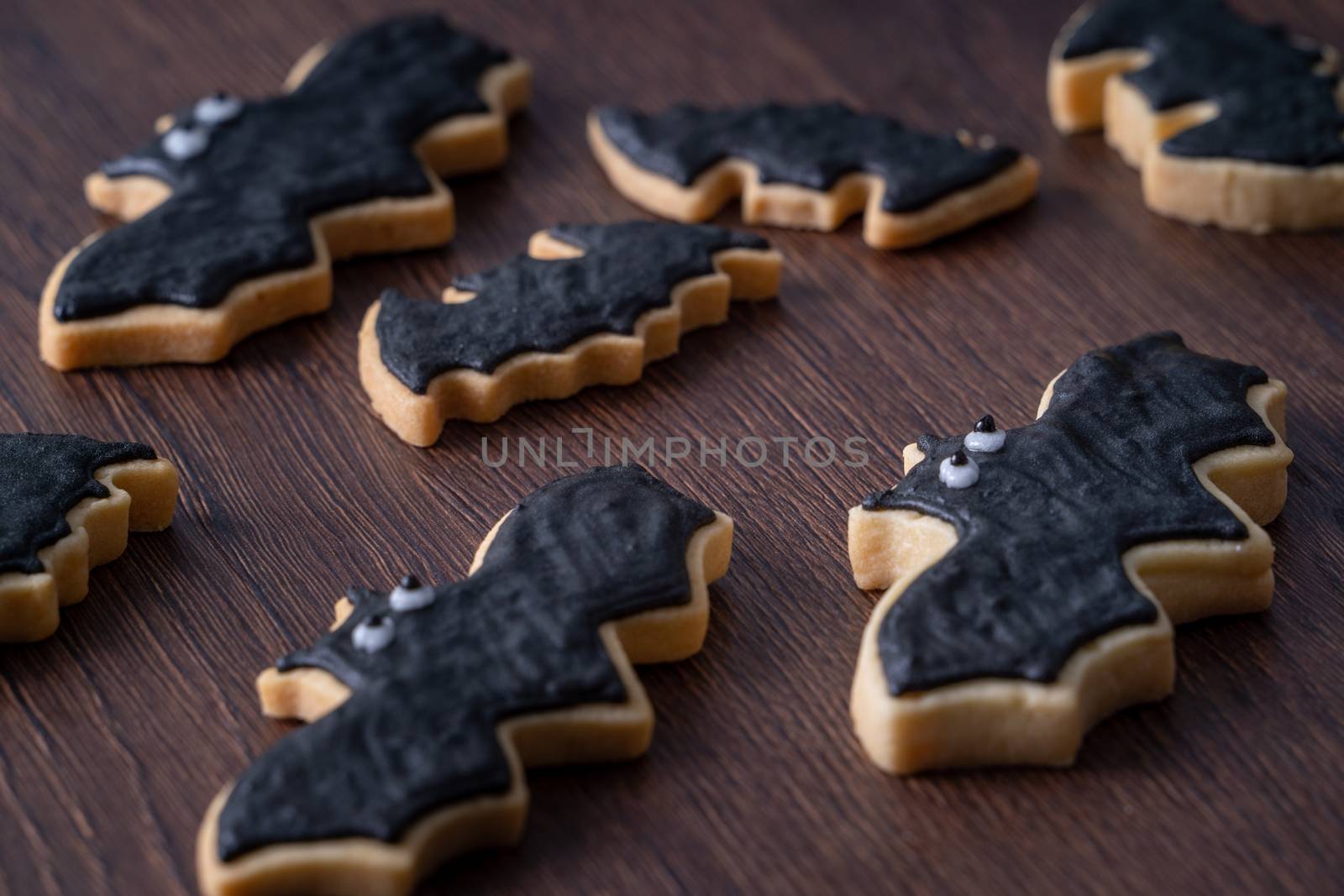 Close up of decorating cute Halloween bat gingerbread sugar cookies with frosting icing cream topping bag.