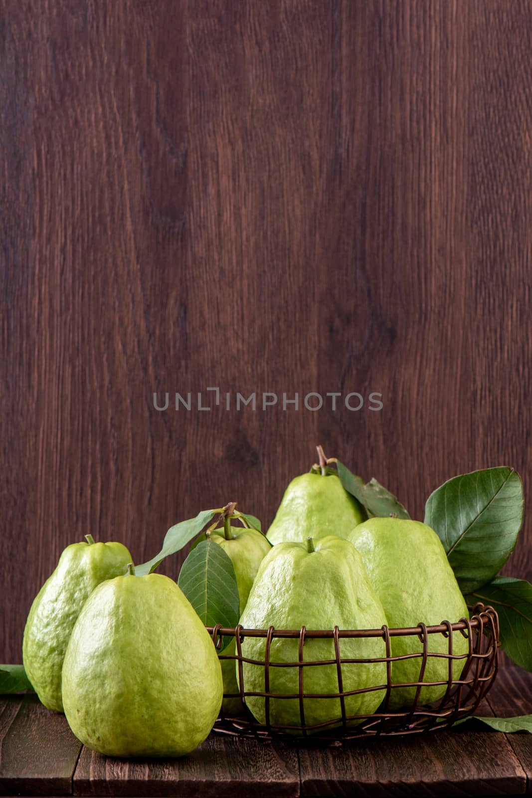 Close up of delicious guava with fresh green leaves on wooden ba by ROMIXIMAGE