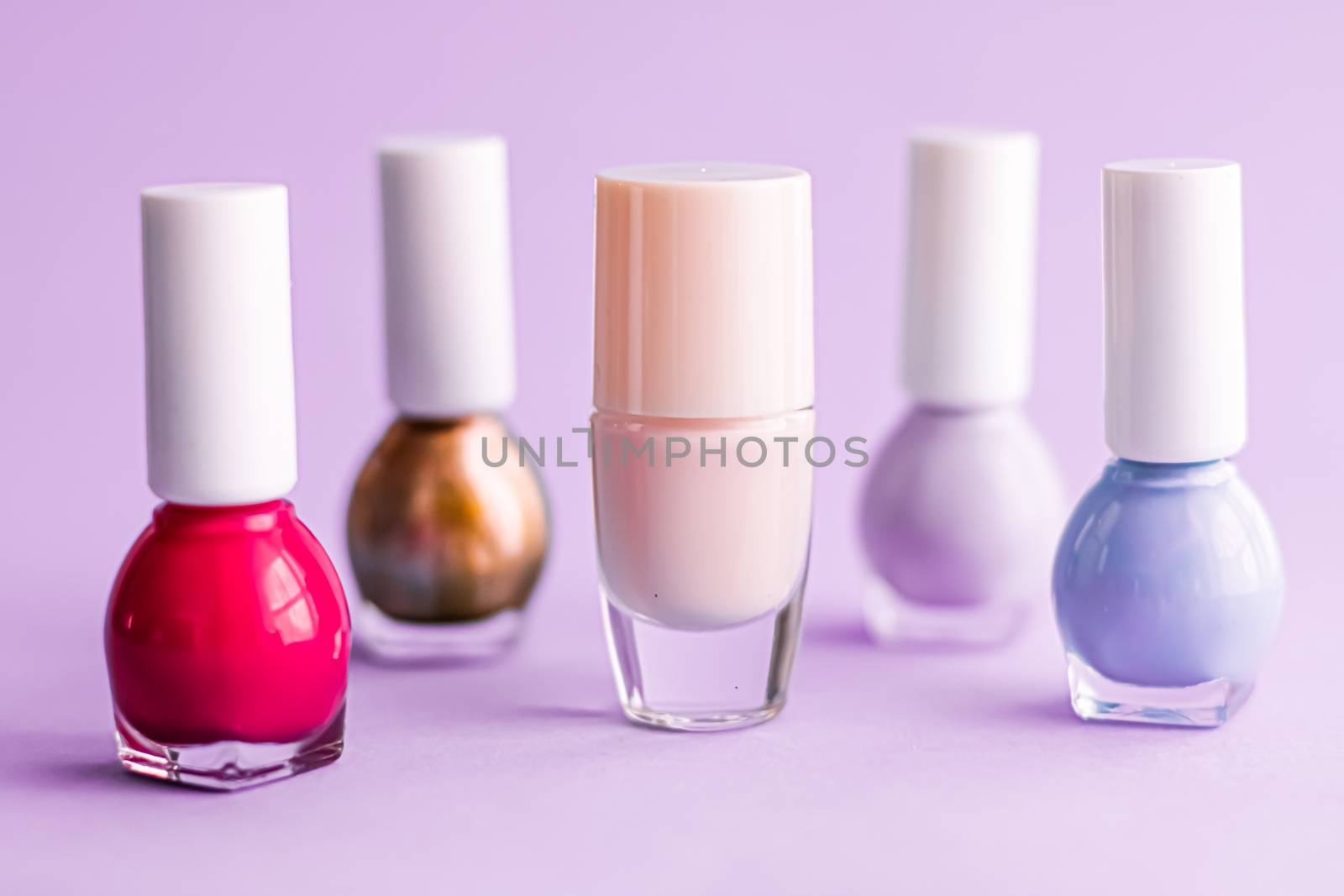 Nail polish bottles on purple background, beauty branding