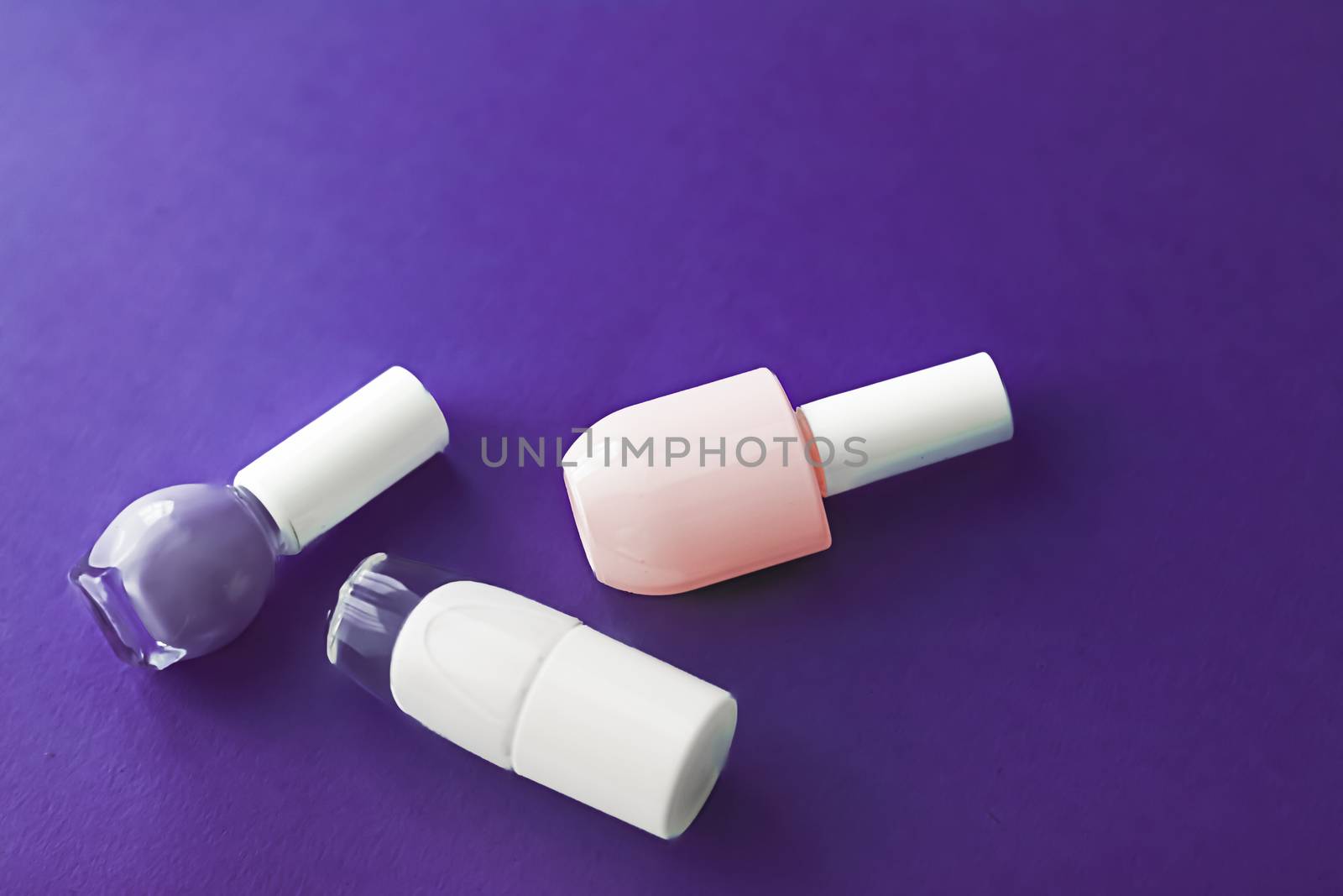 Nail polish bottles on dark purple background, beauty branding