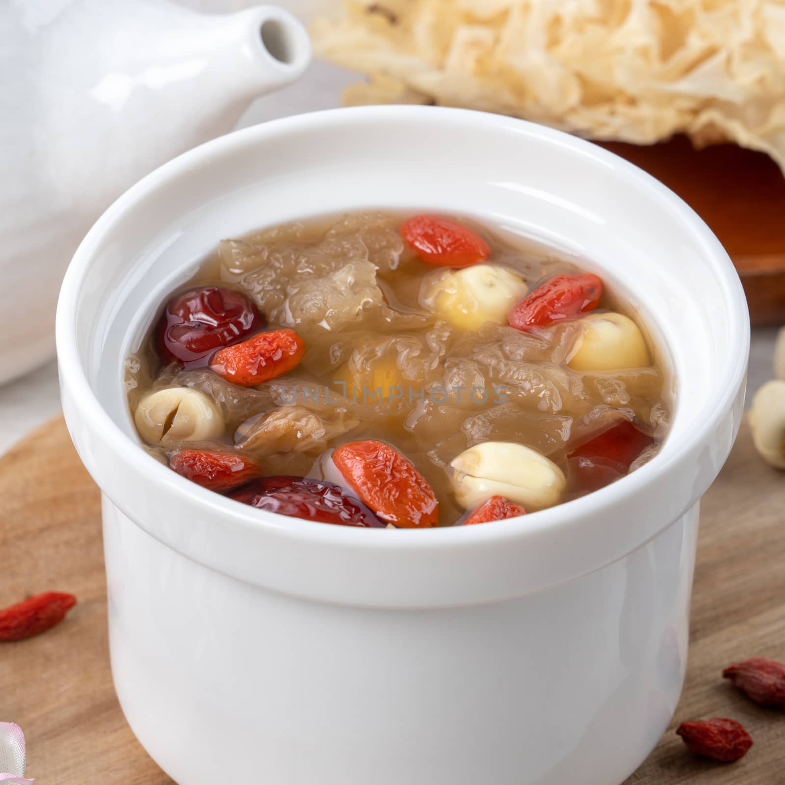 Close up of traditional Chinese sweet snow white fungus soup with lotus seed, red dates (jujube) and wolfberry (goji, gojiberry) on white background.